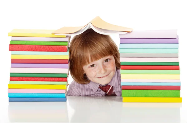 Шкільний хлопчик з великою кількістю різнокольорових книг — стокове фото