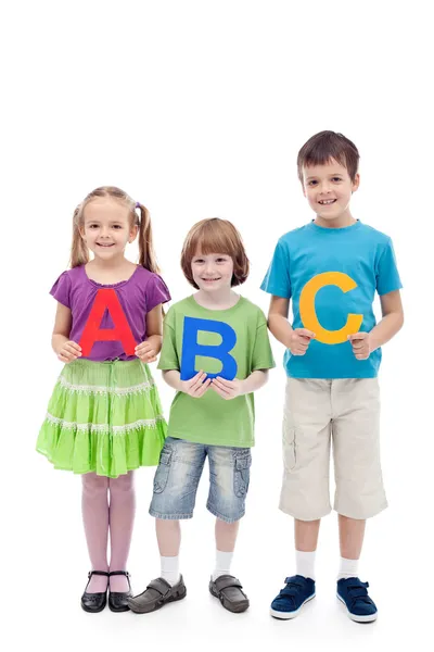 Niños de la escuela feliz sosteniendo grandes letras abc — Foto de Stock