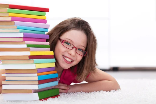 Młody student z dużą ilością książek uśmiechający się — Zdjęcie stockowe