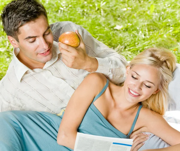 Jeune couple lisant ensemble, en plein air — Photo