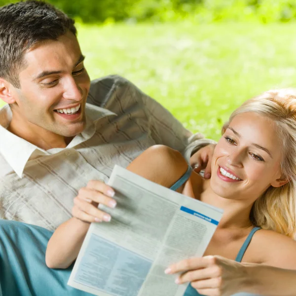 Jovem casal lendo juntos, ao ar livre — Fotografia de Stock