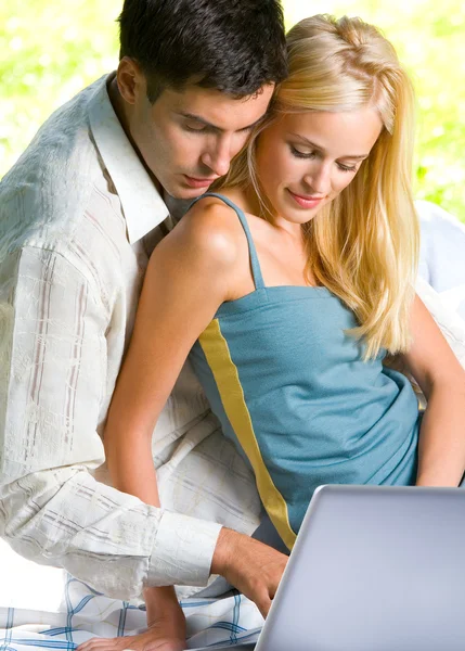 Молодая пара работает с ноутбуком, на открытом воздухе — стоковое фото