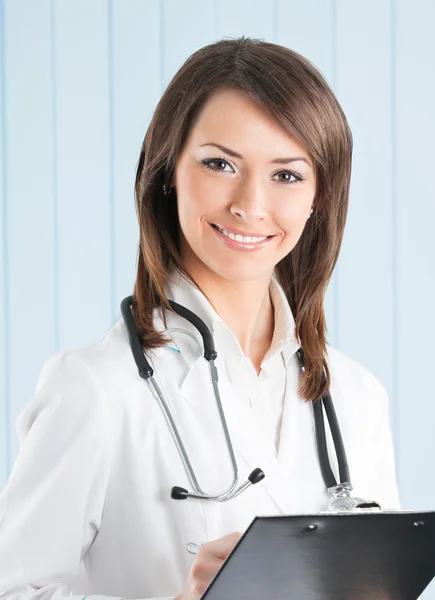 Médica sorridente com prancheta no escritório — Fotografia de Stock