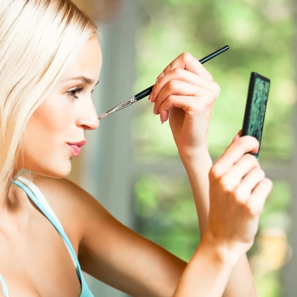 Ung blond kvinna med makeup borste hemma — Stockfoto