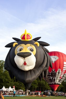 BARNEVELD, THE NETHERLANDS - 17 AUGUST 2012: Colorful lion and red air balloons taking off at international balloon festival Ballonfiesta in Barneveld on August 17 in Barneveld, The Netherlands clipart