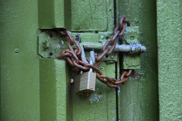 Uma porta verde trancada com cadeado e corrente — Fotografia de Stock