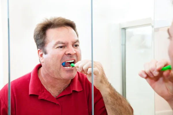 Man zijn tandenpoetsen in badkamer — Stockfoto