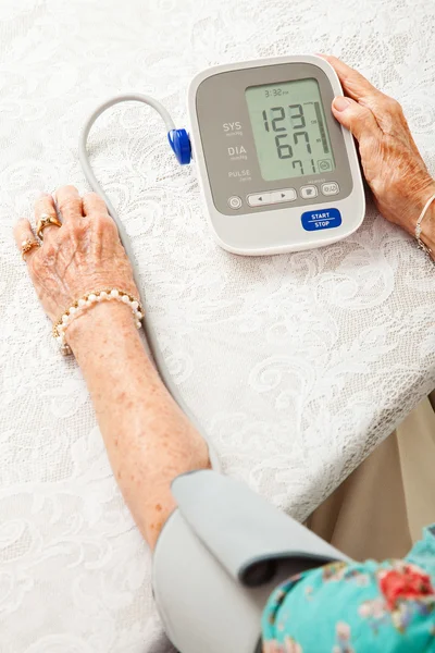 Старшая женщина измеряет давление крови — стоковое фото