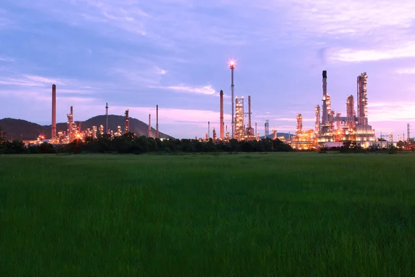 Green grass field with scenic of petrochemical oil refinery plan — Stock Photo, Image