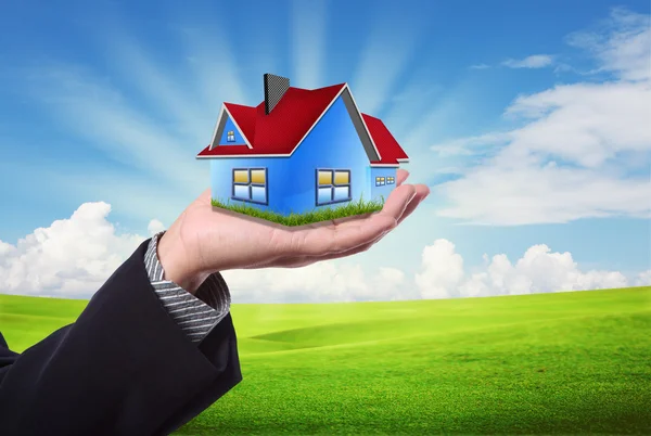 Дом в руках против голубого неба как символ бизнеса недвижимости — стоковое фото