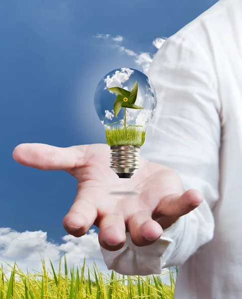 Paddle , windmill and blue sky in light bulb on hand — Stock Photo, Image