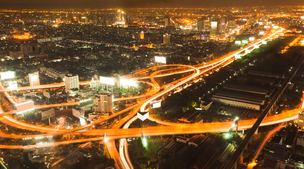 Busy road intersection in the heart of downtown Bangkok, shot at night showing car headlight trails
