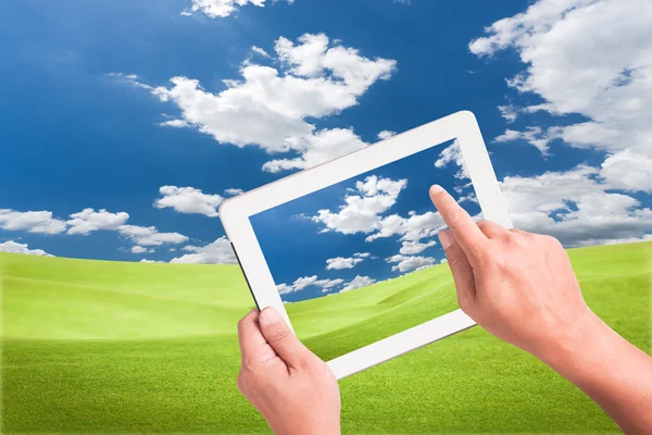 Hand holding a touchpad pc with green field — Stock Photo, Image