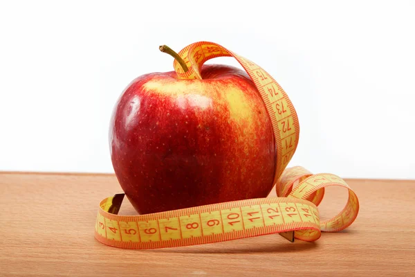Красное яблоко и измерительная лента на деревянном столе . — стоковое фото