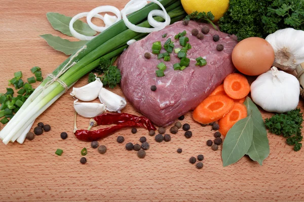 Сырое мясо, овощи и специи изолированы на деревянном столе . — стоковое фото