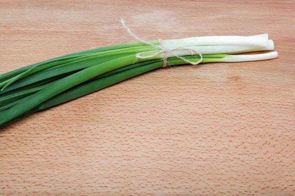 Bunch of fresh green onions on a wooden table. — Stock Photo, Image