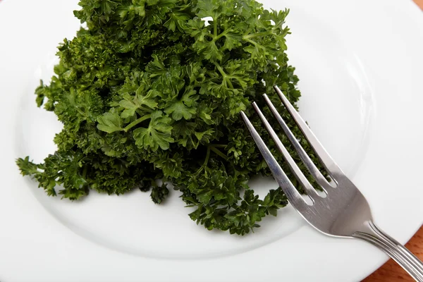 Fresh bunch of parsley on the plate with a fork on a wooden tabl — Stock Photo, Image