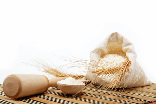 Meel en tarwe graan met houten lepel op een houten tafel. — Stockfoto