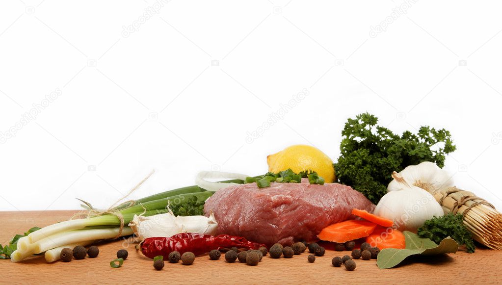 Raw meat, vegetables and spices isolated on a wooden table.