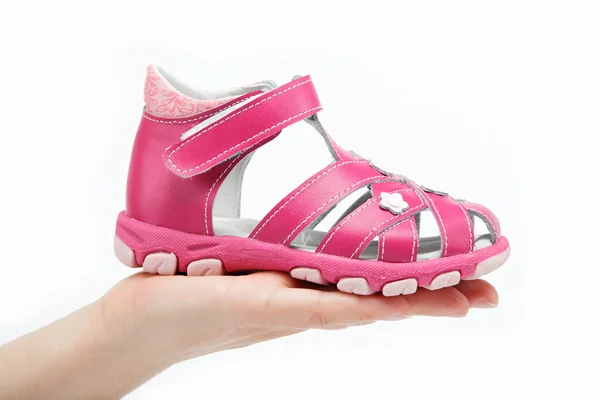 Kinderen sandalen in de women's hand geïsoleerd op wit roze. — Stockfoto