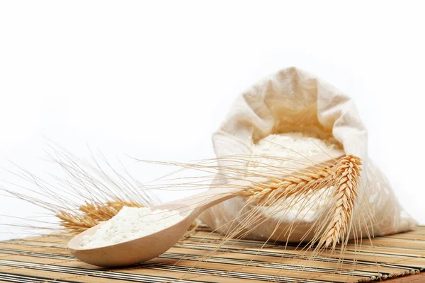 Ziarna pszenicy i mąki z drewnianą łyżką na drewnianym stołem. — Zdjęcie stockowe