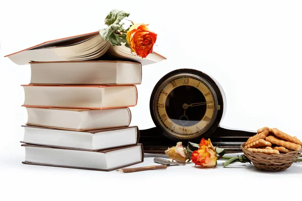 Una pila de libros y un reloj antiguo sobre un fondo blanco . —  Fotos de Stock