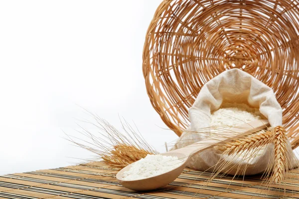 Ziarna pszenicy i mąki z drewnianą łyżką na drewnianym stołem. — Zdjęcie stockowe