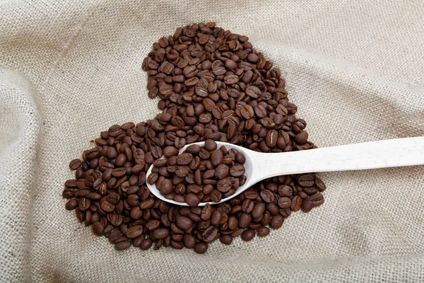 Kahve çekirdekleri ve tahta kaşık ehlileştirmek üzerinde — Stok fotoğraf