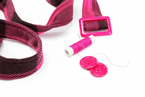 Bobine de fil avec une aiguille, des boutons et une ceinture sur un dos blanc — Photo