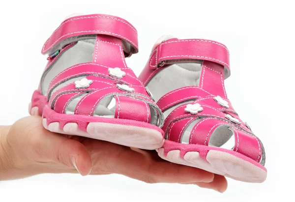 Sandale roz pentru copii în mâna femeilor izolate pe alb . — Fotografie, imagine de stoc