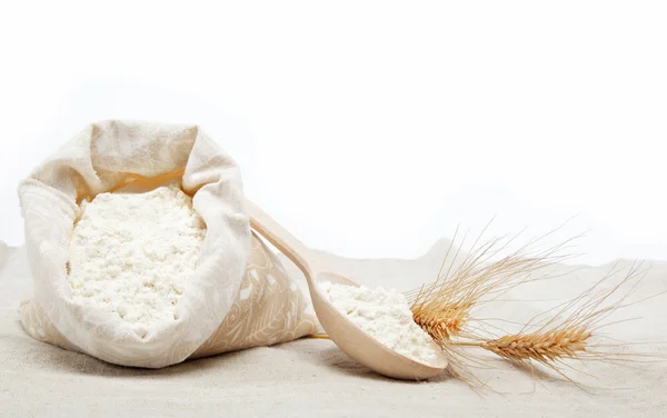 Mehl und Weizenkorn auf Sacktuch über weißem — Stockfoto