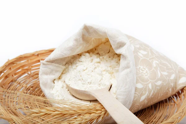 Flour and wheat grain with wooden spoon on a wicker basket. — Stock Photo, Image