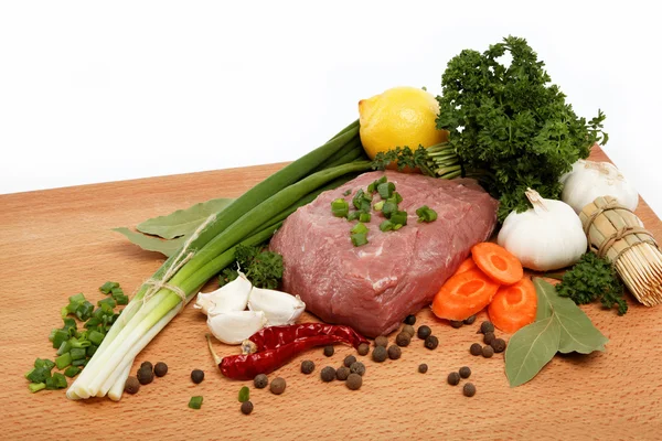 Çiğ et, sebze ve ahşap bir masaya izole baharat. — Stok fotoğraf