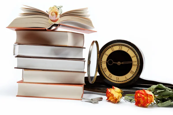 Una pila de libros y un reloj antiguo sobre un fondo blanco . — Foto de Stock
