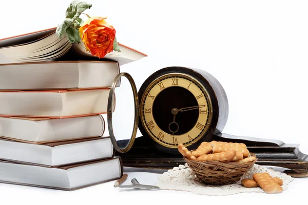 A stack of books and antique clock on a white background. — Stock Photo, Image