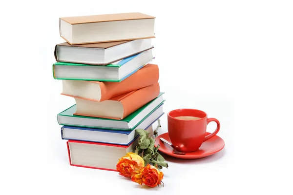 Uma pilha de livros e uma xícara de café em um pires em uma parte traseira branca — Fotografia de Stock