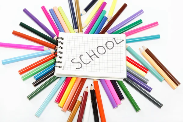 Blocco note su uno sfondo di matite colorate . — Foto Stock