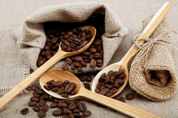 Grãos de café em uma colher em saquear . — Fotografia de Stock