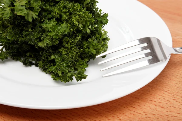 Fresh bunch of parsley on the plate with a fork on a wooden tabl — Stock Photo, Image