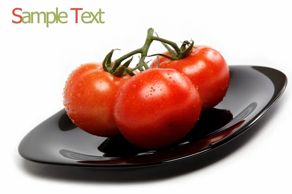Färska tomater på en tallrik, isolerad på en vit bakgrund. — Stockfoto