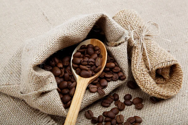 Kaffebönor i en sked på säckväv. — Stockfoto