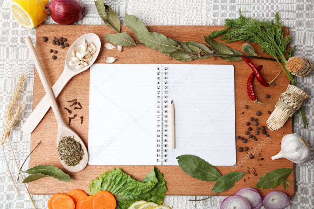 Notebook for recipes and spices on wooden board.