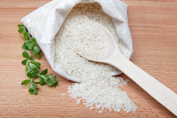 Rice in a bag and a spoon on a wooden table. — Stock Photo, Image