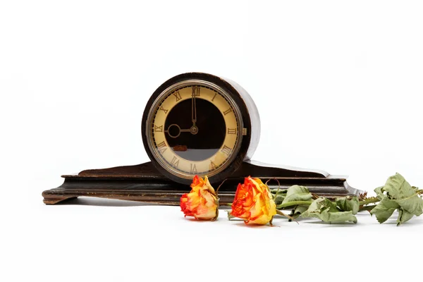 Antico orologio da tavolo in legno e rose secche su sfondo bianco . — Foto Stock