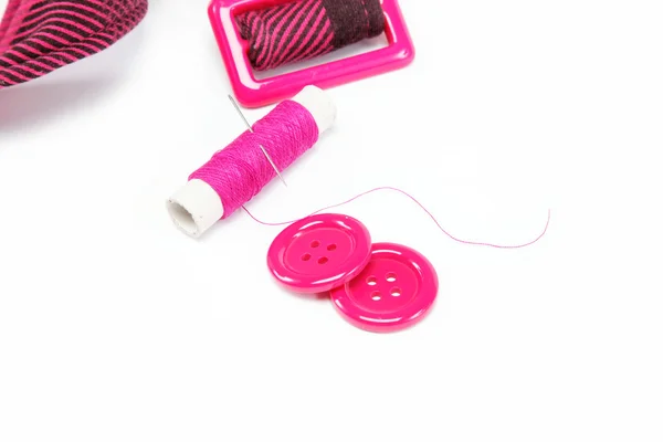 Bobine de fil avec une aiguille, des boutons et une ceinture sur un dos blanc — Photo
