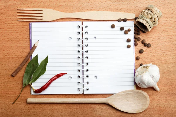 Caderno de receitas e especiarias em mesa de madeira — Fotografia de Stock