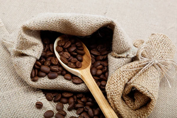 Grains de café dans une cuillère sur le sac . — Photo