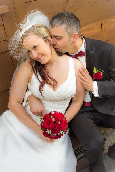 刚刚结婚的年轻夫妇坐在门廊和接吻 — 图库照片