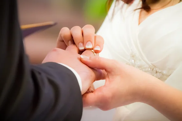 stock image Groom puts ring on brides finger in church