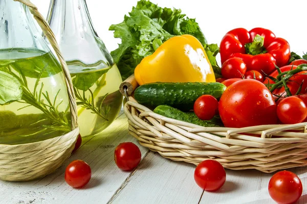Olivolja i en flaska och korg med grönsaker — Stockfoto